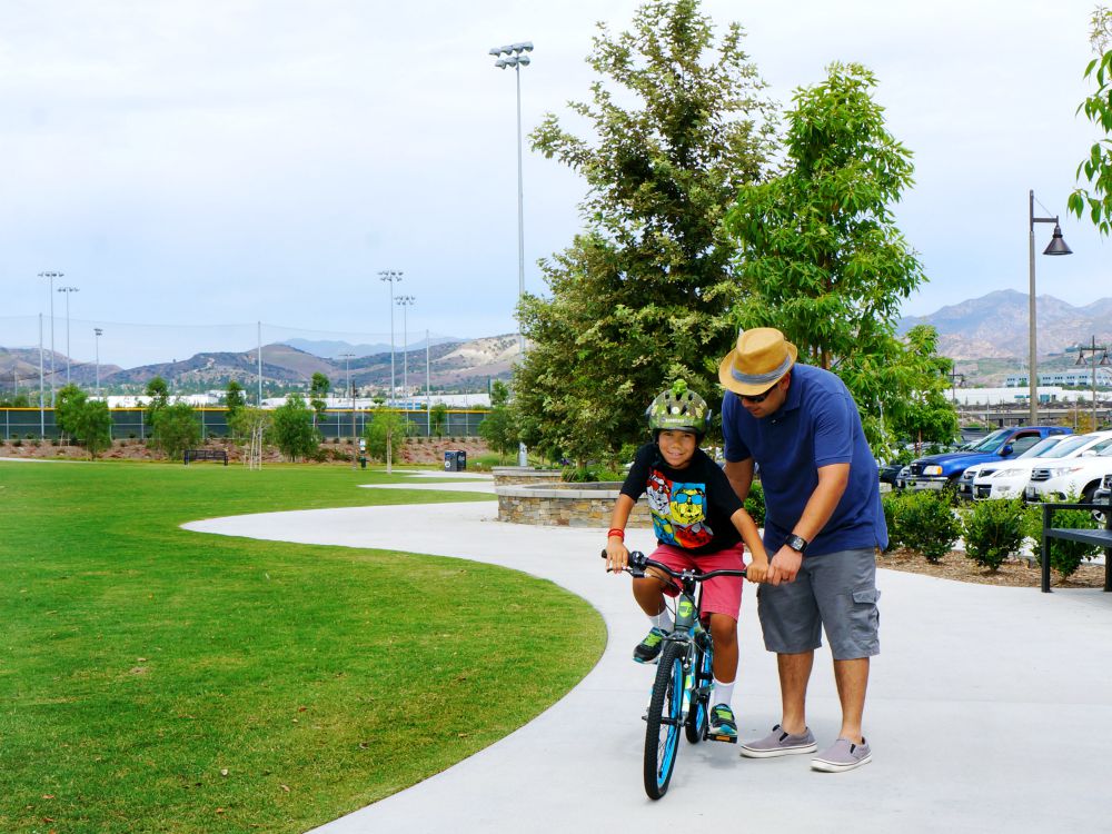 Dad helping son learn how to ride a bike