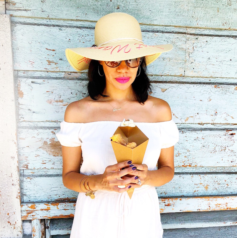 Girl holding churro bites wearing a white sunhat - livingmividaloca.com