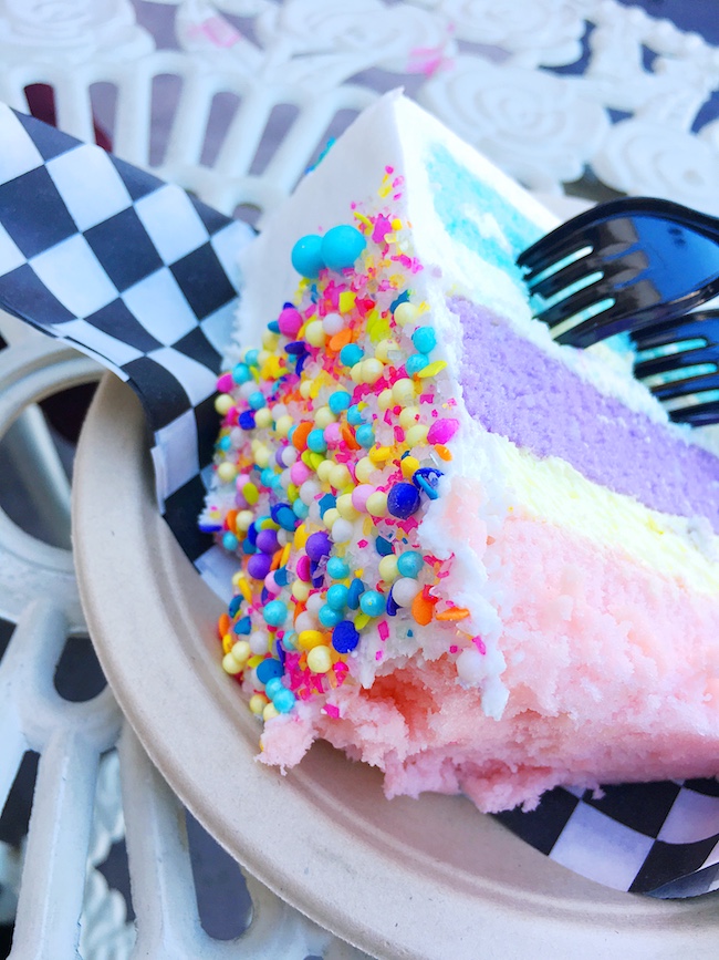 Unicorn cake with sprinkles on black and white checked paper.   #unicornfoods #unicorncake #unicorns #partyfood #unicornparty #unicorntreats #unicornpartytreats  livingmividaloca.com