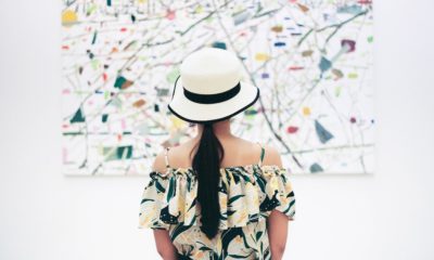 young woman wearing white hat standing looking at artwork