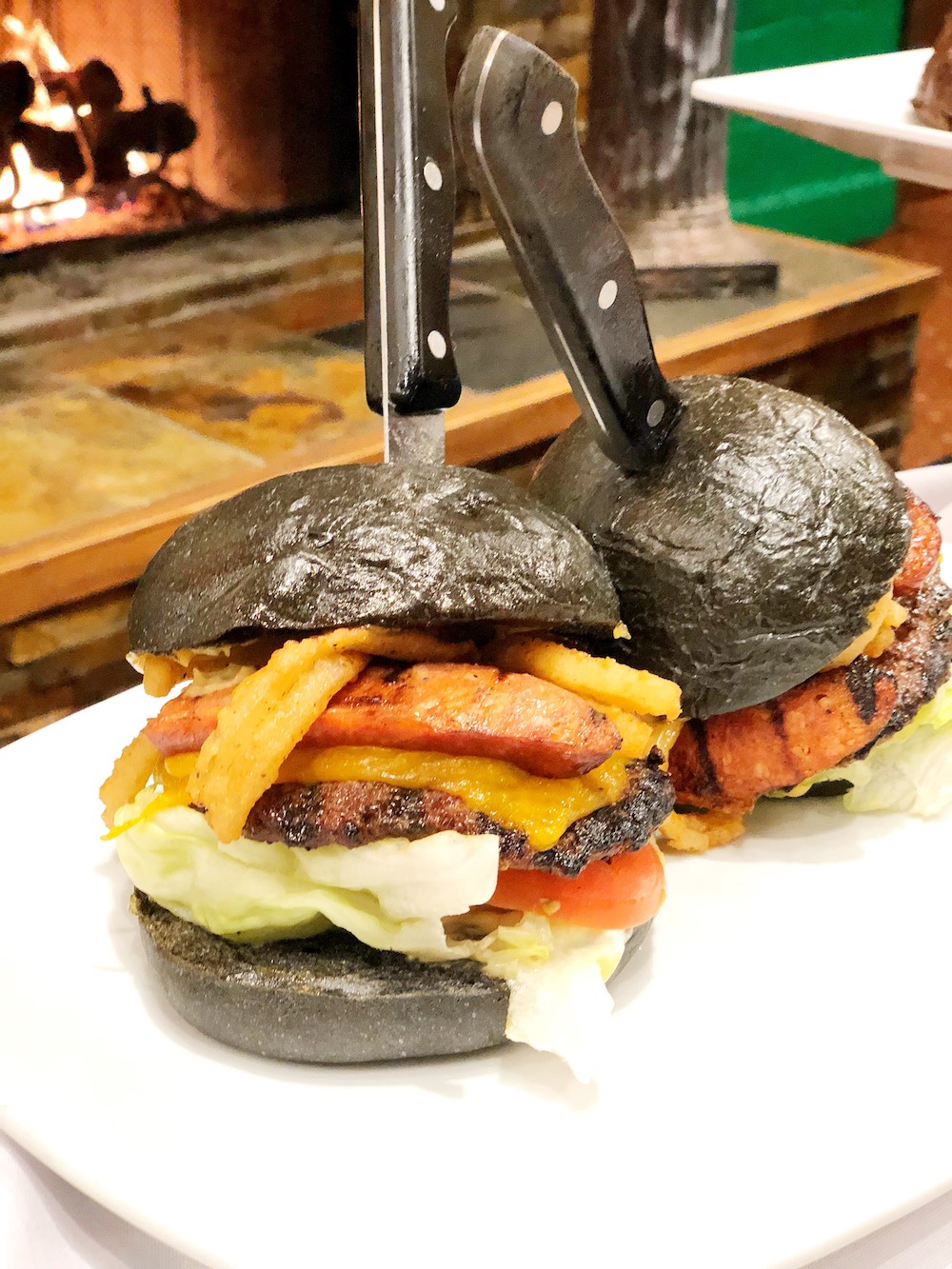Lights out monster burger is served on a black bun. Get it during Knott's Spooky Farm | livingmividaloca.com | #scaryfarm #knottsberryfarm #flaminghotcheetos #themepark #amusementpark #familytravel #california #southerncalifornia