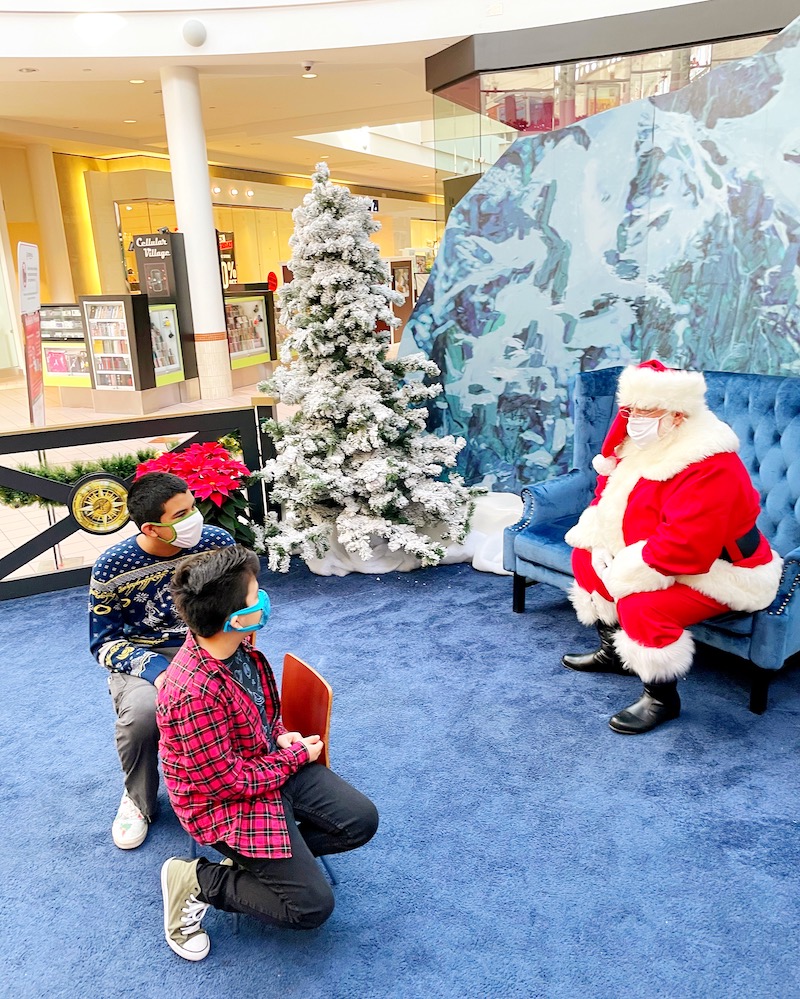 A shopping mall clerk welcomes Christmas shoppers with balloons in Costa  Mesa, CA. Note model of snow covered village at left Stock Photo - Alamy